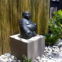 Concrete Chinese Buddha statue on raised podium, pebbles, wooden screens.