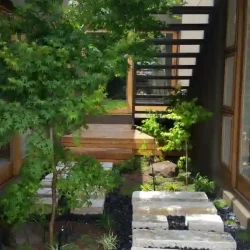 Modern Japanese garden, sandstone slabs as stepping stones in I-Ching patterns, small Zen meditation benches, black pebbles, Japanese Maple tree, wooden decking.