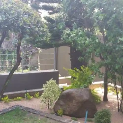 Dropped garden bed with shaped evergreens, large rocks & gravel.