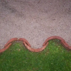 Roof tiles used on edge as lawn or bed edging. Border. Lawn and beige gravel.