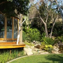 Forest garden with waterfall and pond. Large rocks. Raised deck.