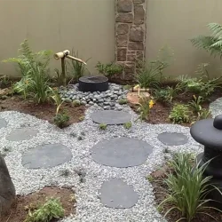 Japanese garden with water pot, bamboo water feature, Japanese lantern, black slate steppingstones, grey gravel.