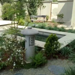 Meditation pond with modern round Japanese lantern, bench.