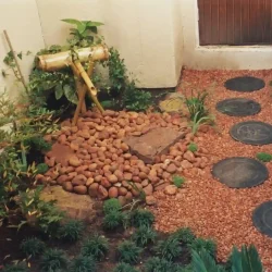 Japanese bamboo water feature, pebbles, decorative round black Japanese steppingstones.