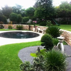Round swimming pool with two curved Japanese garden beds on either side.