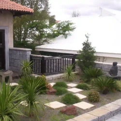 Contemporary meditation garden with Buddha on raised podium and small Zen bench. Low maintenance. Square concrete pavers with gravel .Ornamental grasses and architectural plants.