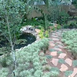 Stroll garden with pond. Natural stone path. Ornamental grasses.