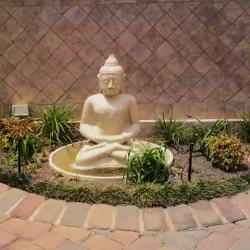 Life-size beige concrete Buddha water feature on driveway